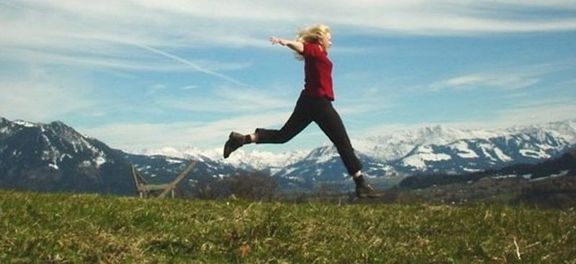 Woman jumping in front of a mountain view.